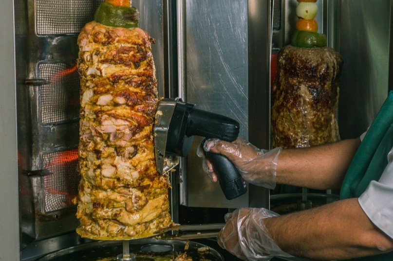 Chicken doner being carved fresh from the vertical spit